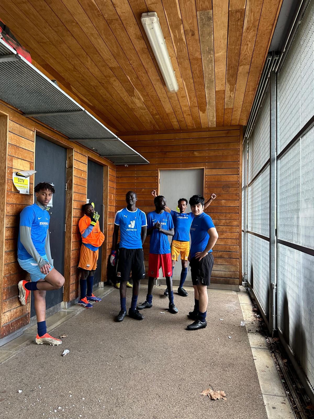 a group of footballers in blue shirts wiating outside the changing rooms