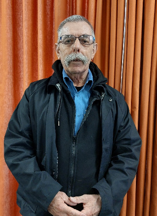 A man standing in front of an orange curtain